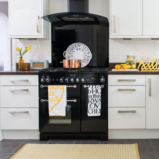 kitchen area with white kitchen units and black stove with oven and chimney