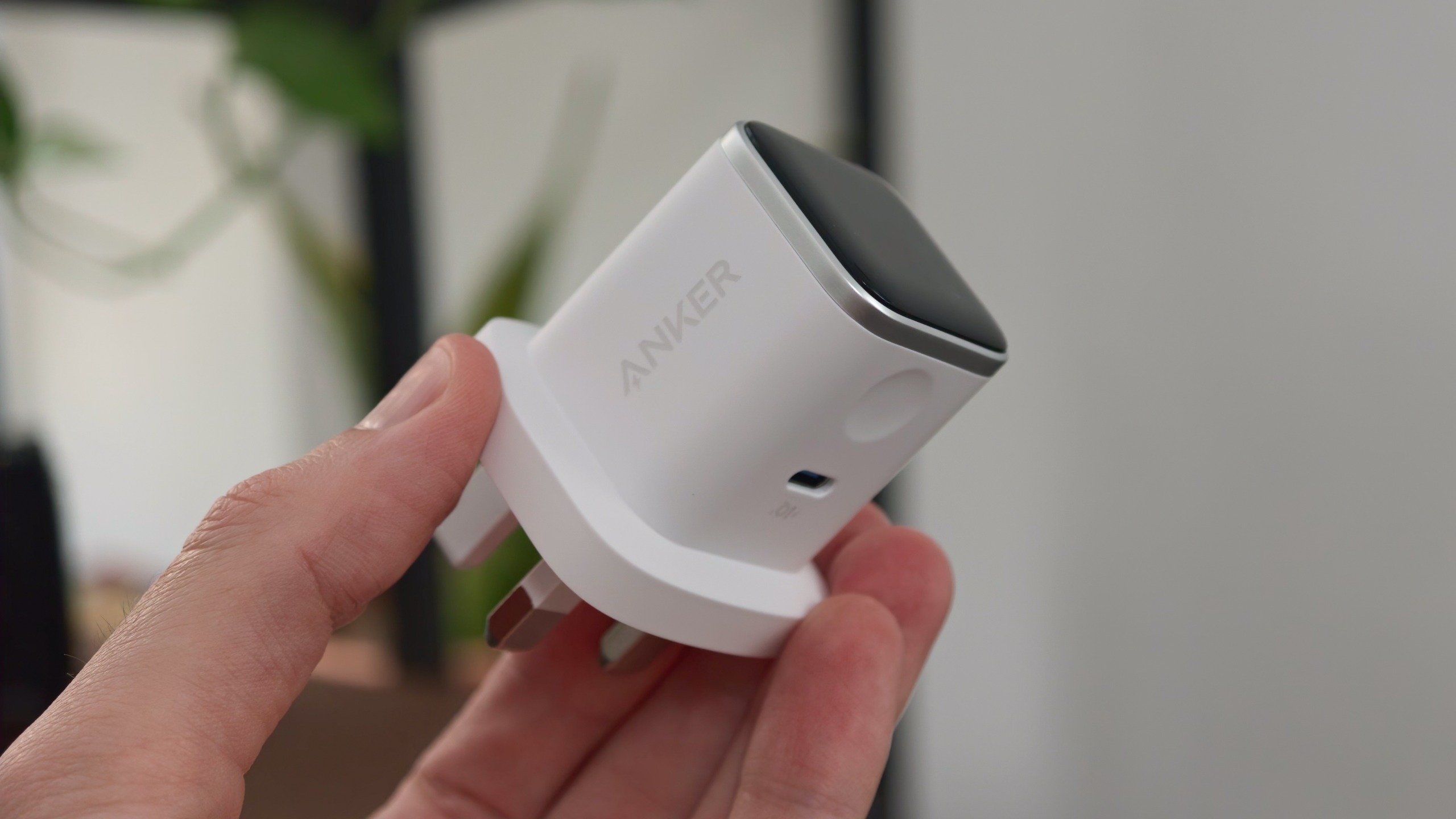 Close-up of the Anker Nano Charger held in a hand, showing its smart display, side button, and compact body.