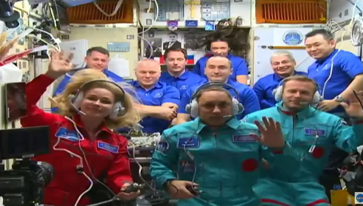 Russian actress Yulia Peresild (bottom left), cosmonaut Anton Shkaplerov (bottom center) and film director Klim Shipenko wave after joining the seven Expedition 65 crewmembers of the International Space Station on Oct. 5, 2021 following a swift launch and docking.