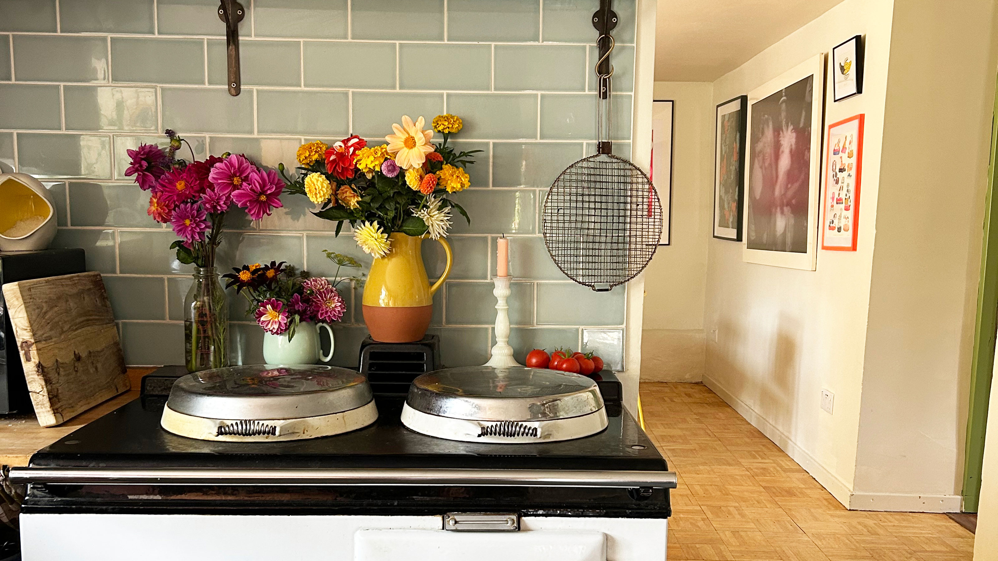 Vases on flowers in front of pale green tiled splashback on top of white AGA