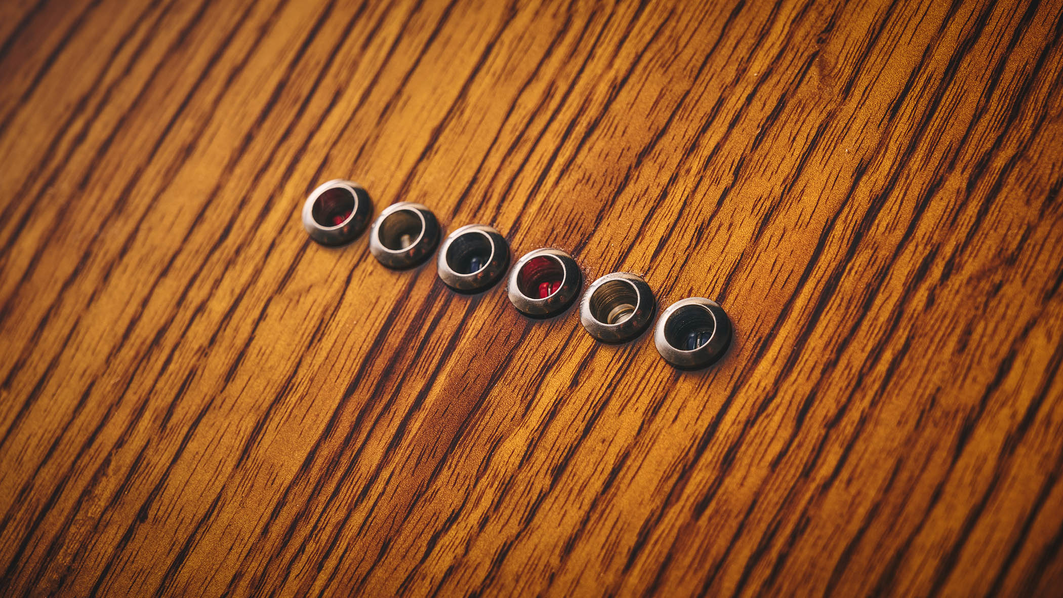 Patrick James Eggle Oz-t Cabronita Thinline; this semi-hollow T-style has a dark sunburst that reveals all the open grain, complementing the tortoiseshell pickguard, and is photographed here against a distressed floor, white and wooden backgrounds.