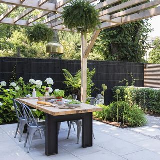 outdoor dinning table with chairs wooden roof and plants