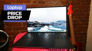 Dell XPS 15 laptop on a red blanket with red guitar and brick wall background