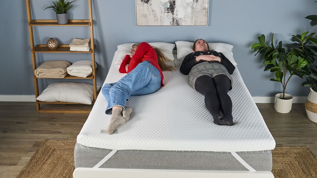 Two testers sleep on the Helix Dual Comfort Mattress Topper. One tester sleeps on her side (left of image), while the other tester (right of image) sleeps on her back.