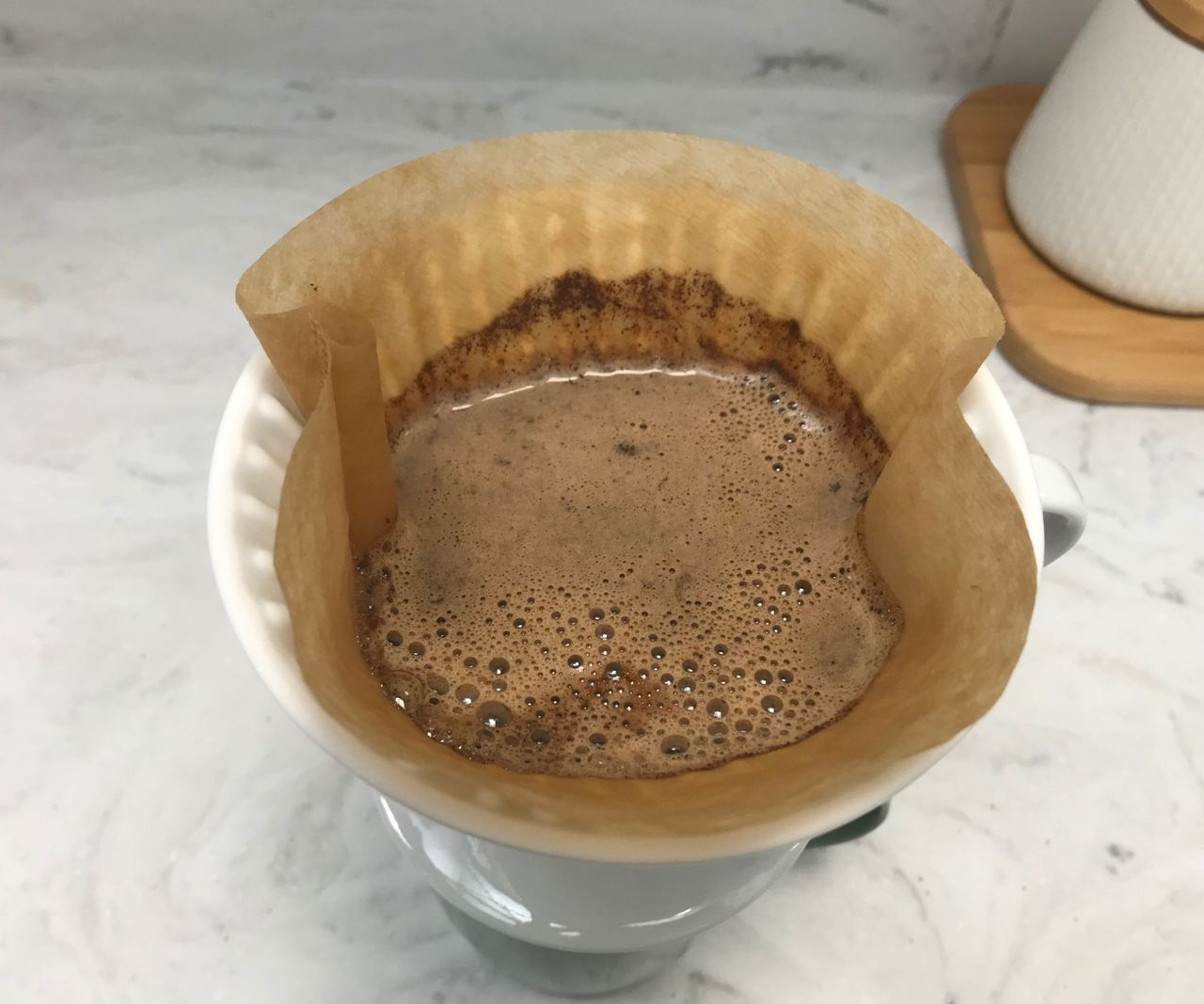 A paper coffee filter with water and goffee grounds inside.