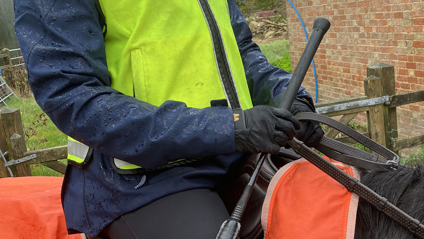 A close up of a rider dressed in high-vis with the horse with a high-vis exercise sheet ready to hack out.