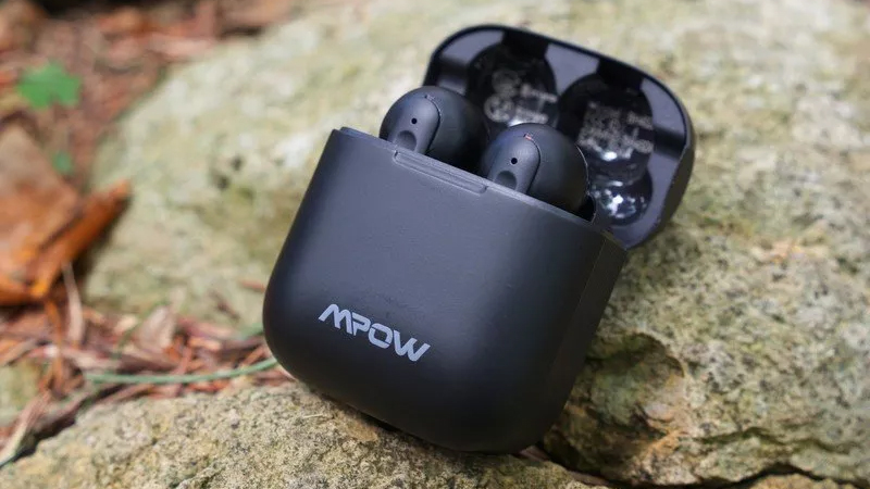 Mpow X3 earbuds lying on a rock with open case.