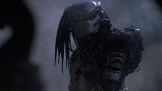 The Predator alien stands in a smoky jungle in Predator