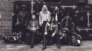 The Allman Brothers Band in an alleyway in front of their flight cases, smiling.