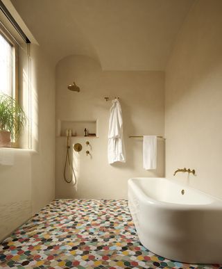 plastered wet room with bathtub and patterned multicolor tiles