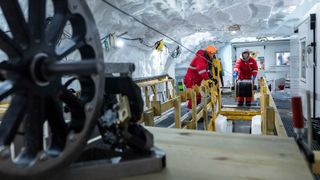 Researchers lower a fiber-optic cable into a borehole in the ice.