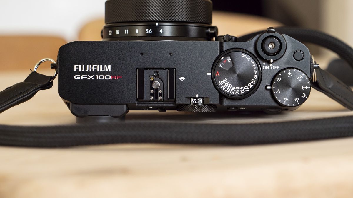 All-black Fujifilm GFX100RF rangefinder-style camera on a wooden table