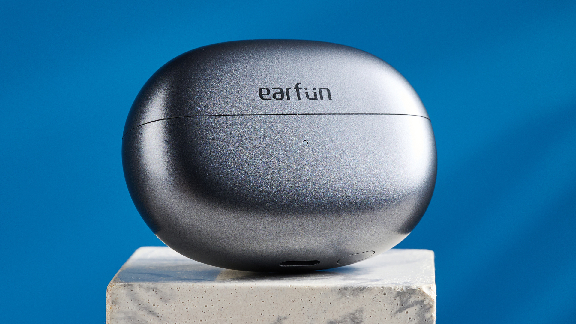 EarFun Clip open-earbuds photographed in front of a blue background.