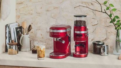 kitchenaid espresso machine and grinder on a surface with coffee around it
