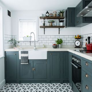 Shaker kitchen cupboards with brass handles and decorative floor tiles and metro tile splashback