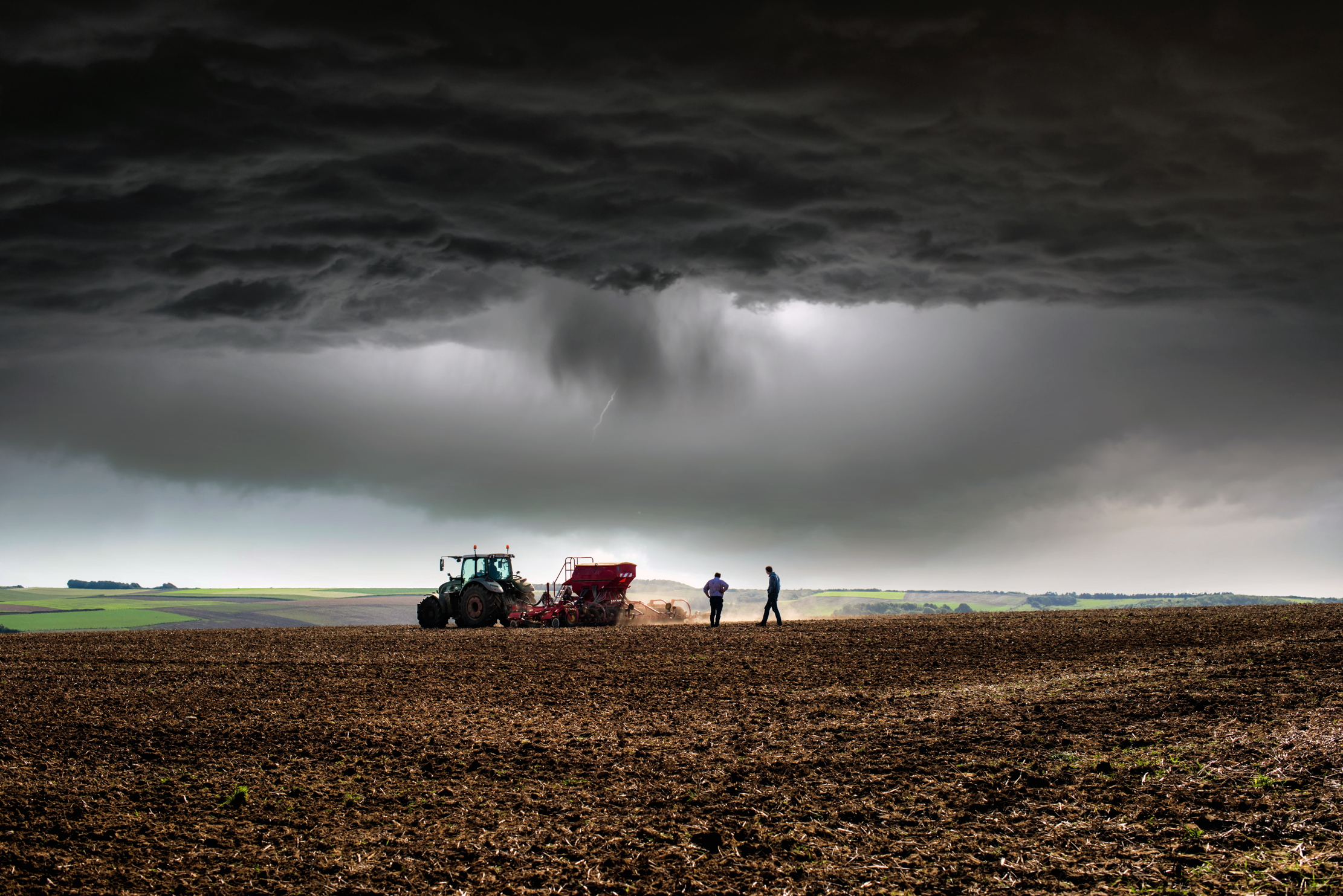 Farmers stand in a field as the sky opens up around them