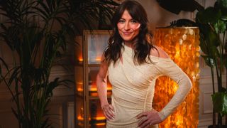 Davina hands on hips wearing yellow dress at the Stranded on Honeymoon Island speed-dating event