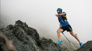 A man fastpacking with hiking poles