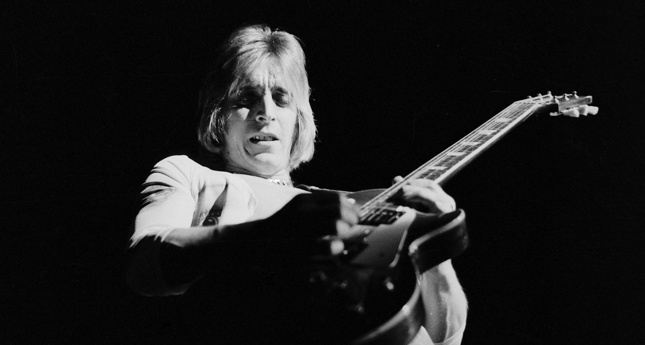 A black-and-white action shot of Mick Ronson in 1975