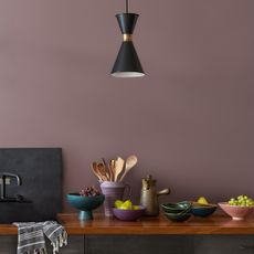 Kitchen wall painted in Benjamin Moore's Cinnamon Slate with warm wood worktop dressed with muted ceramics