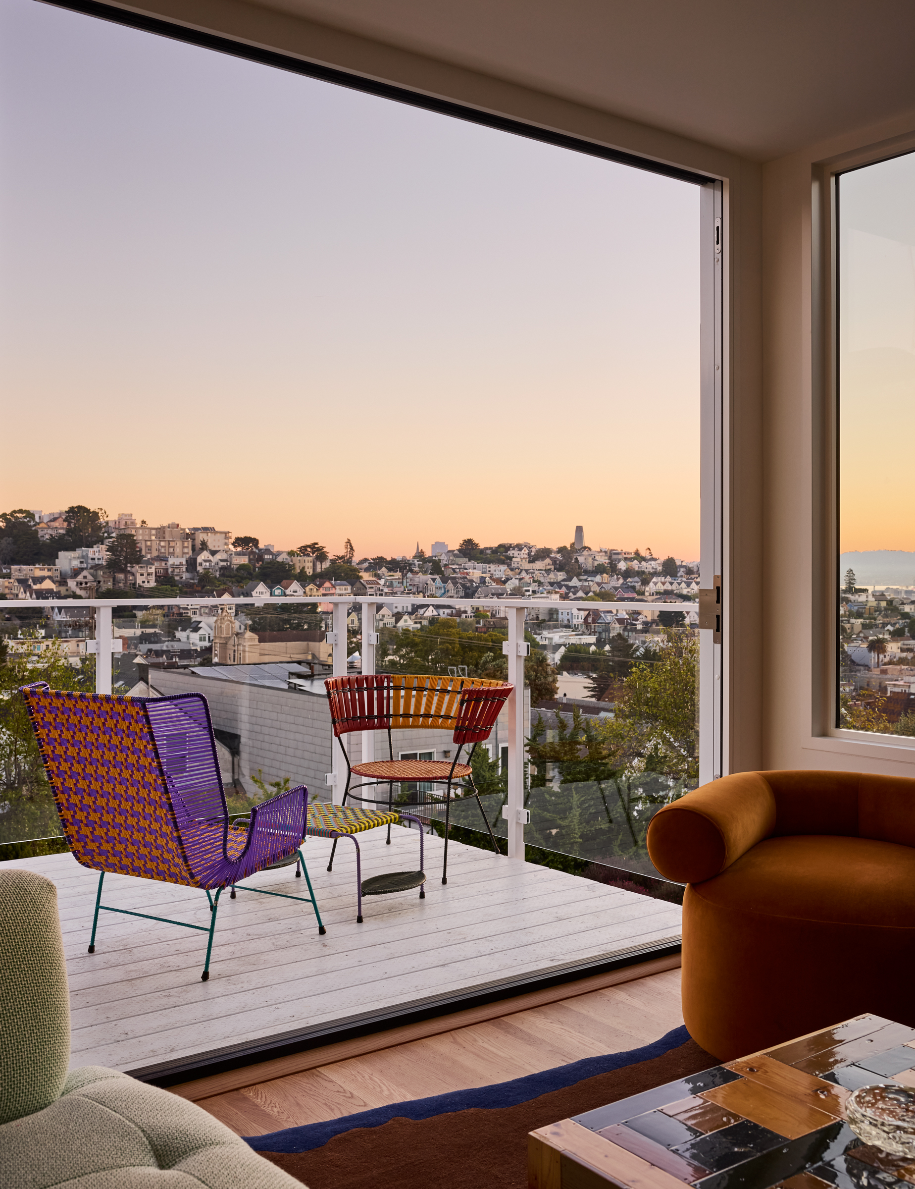 A large balcony or terrace overlooking the San Francisco Bay with two outdoor chairs and a small coffee table