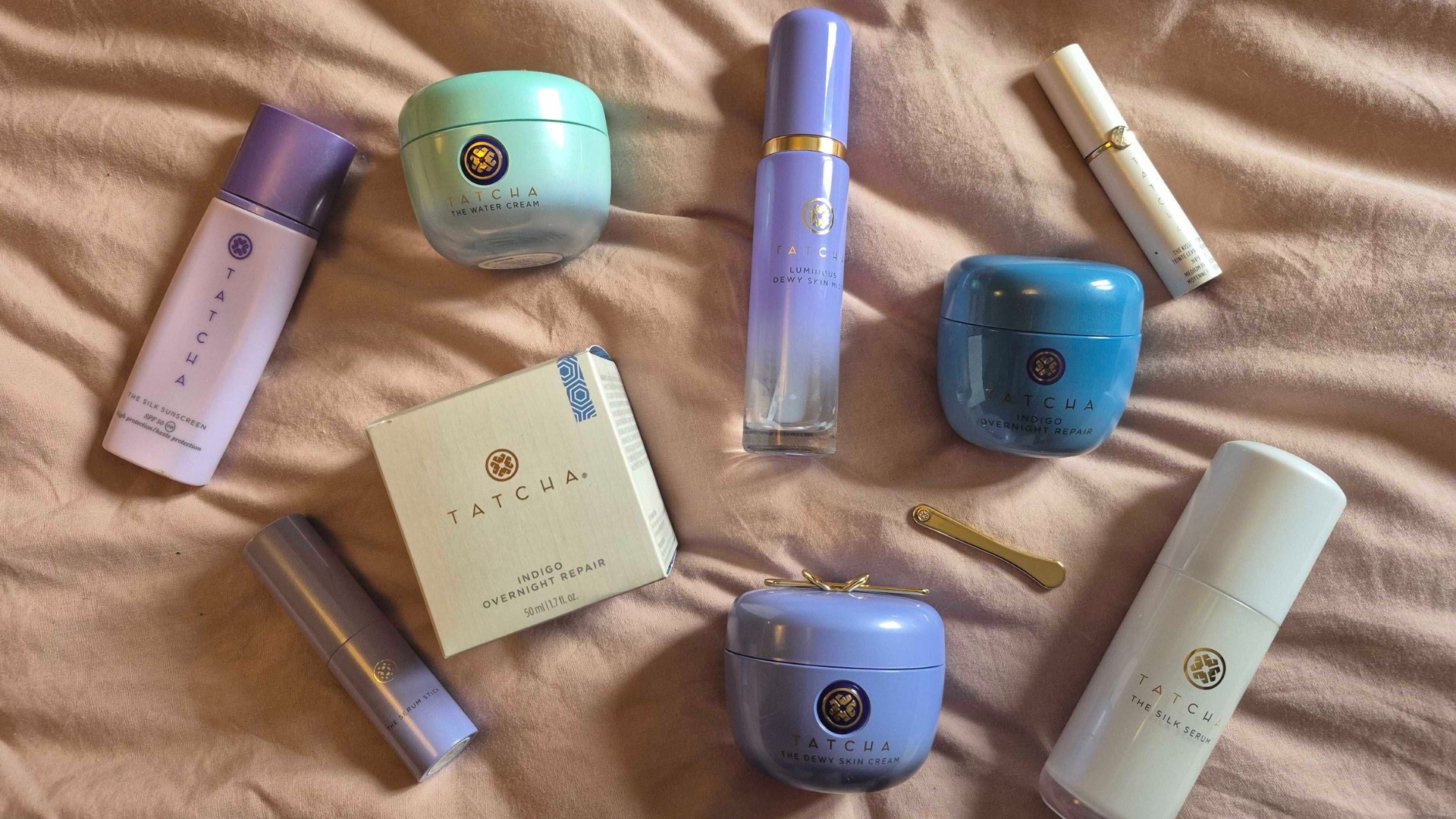 A variety of Tatcha products laid out on a bed