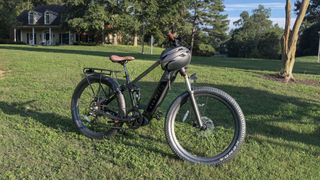 Mod Bikes Black 3 electric bike stopped in a park with a helmet handing on the handlebar