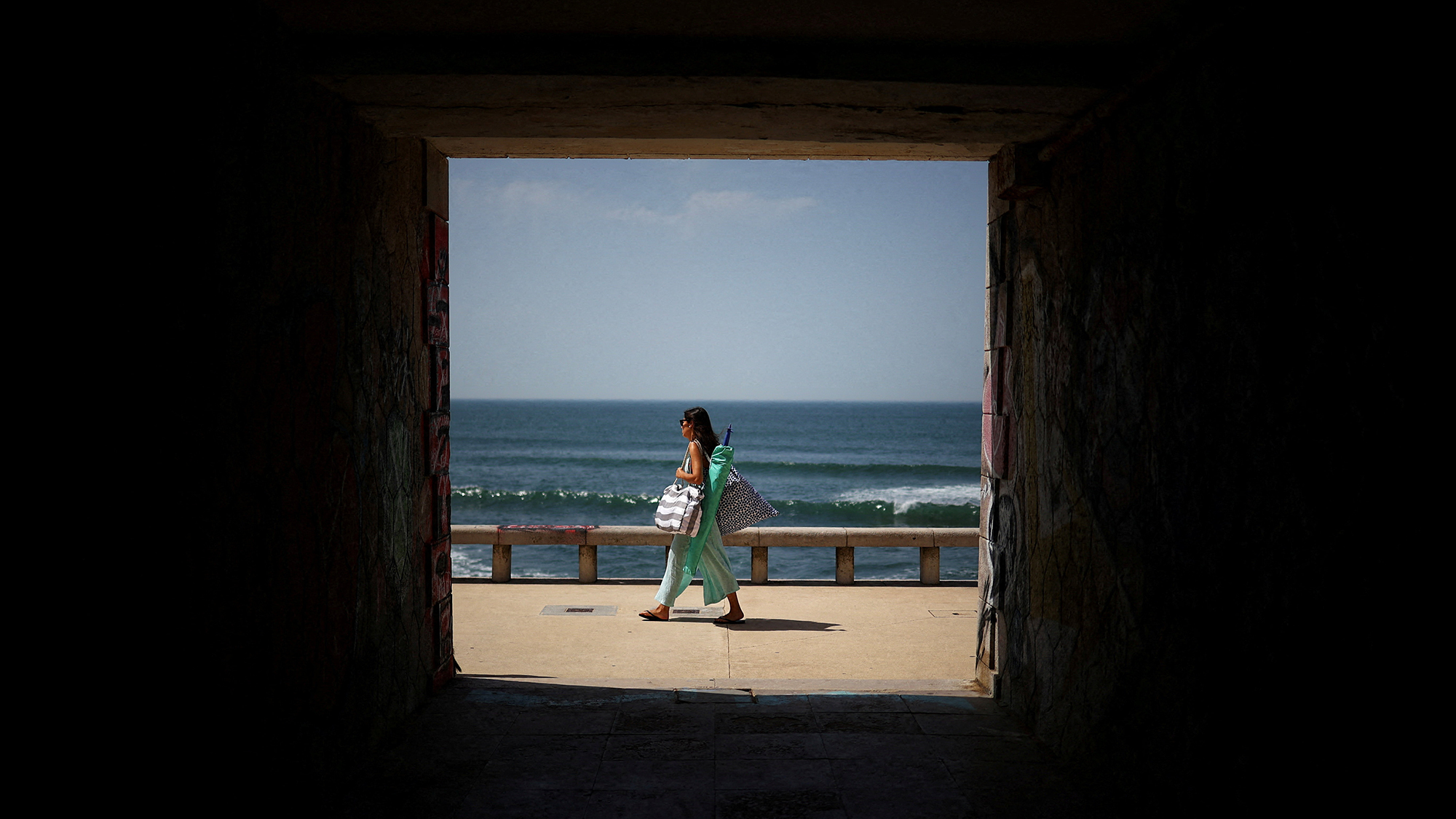 A woman arrives at Parede Beach during a heatwave in Cascais, Portugal
