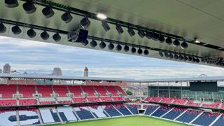 An outdoor stadium adorned with an L-Acoustics sound system hanging from the upper deck.