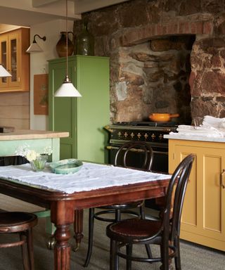 devol green and yellow kitchen with center table and exposed brick