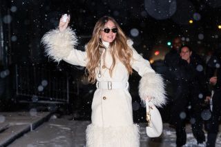 Sydney Sweeney wearing an all white coat and throwing a snowball with her left hand while out in New York City on January 19, 2025.