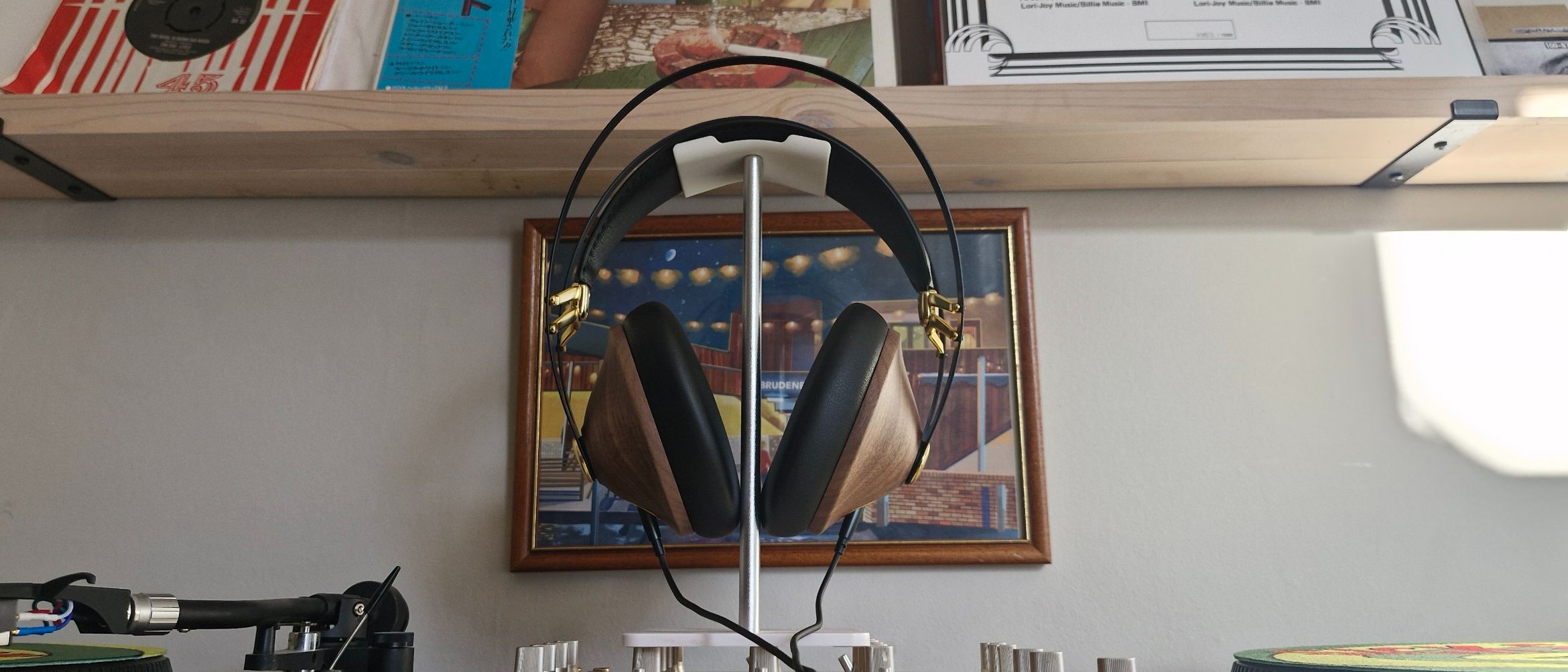 Meze Audio 99 Classics 2nd Gen wired headphones, on a headphone stand, in front of a bookshelf and a framed picture