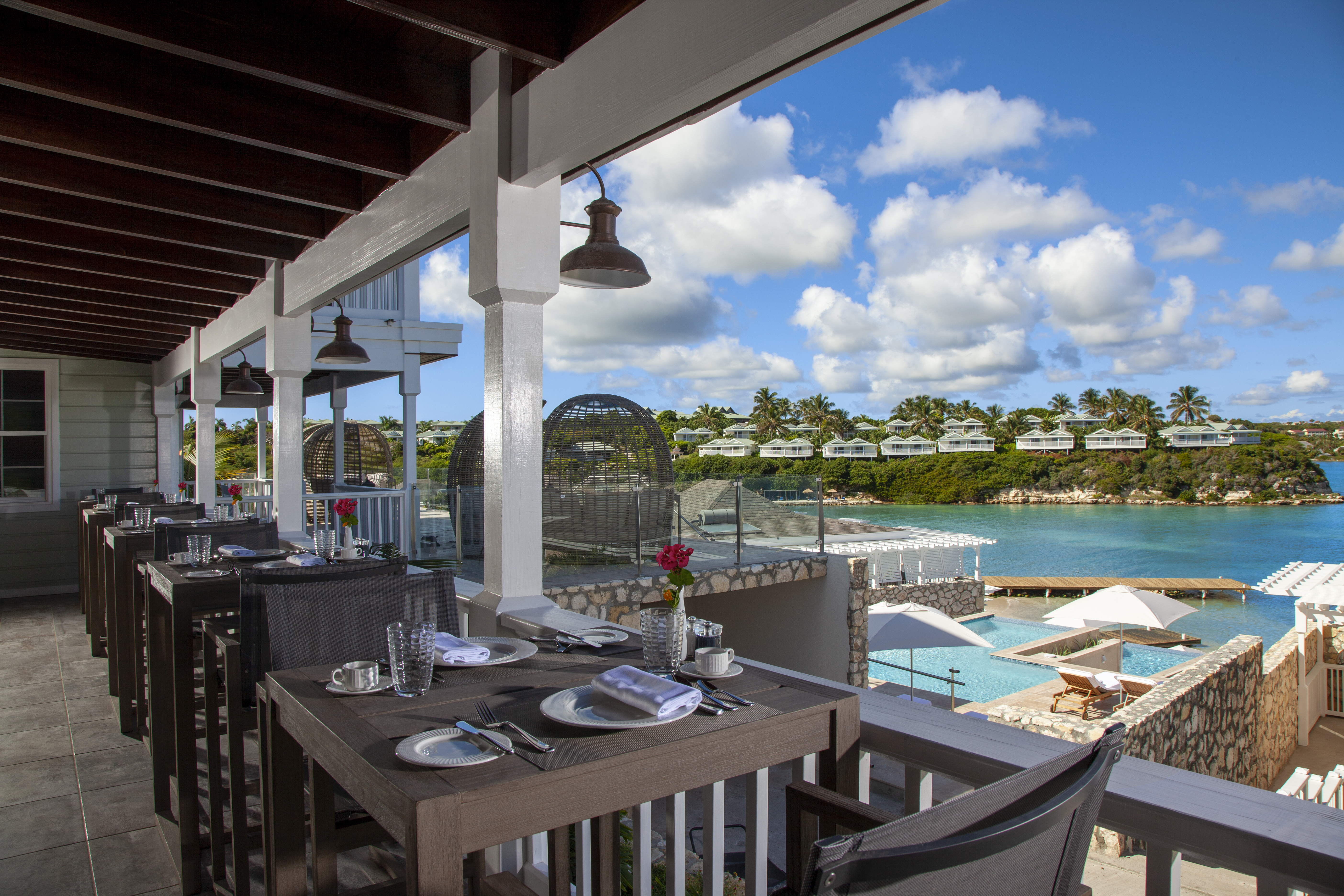 A view of an outdoor pool and beach from Irina&#039;s Bistro at Hammock Cove Antigua.