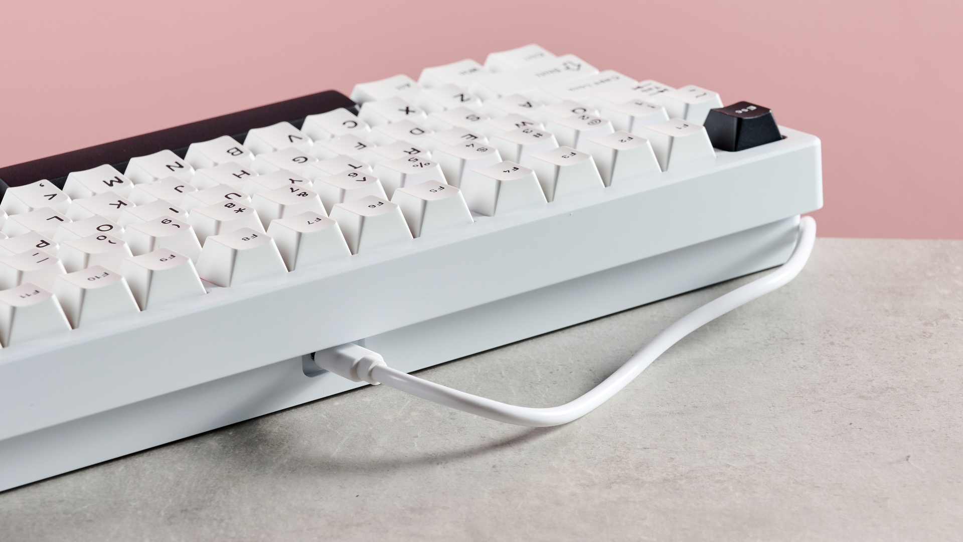 Back of Wobkey Rainy 75 Pro with USB cable attached, on desk with pink background
