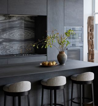 a dark gray minimalist kitchen with a marble backsplash