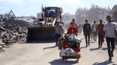 Bulldozers drive past displaced Palestinians walking through Gaza City