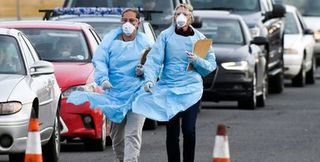 Health care workers in protective equipment at a drive through test center.