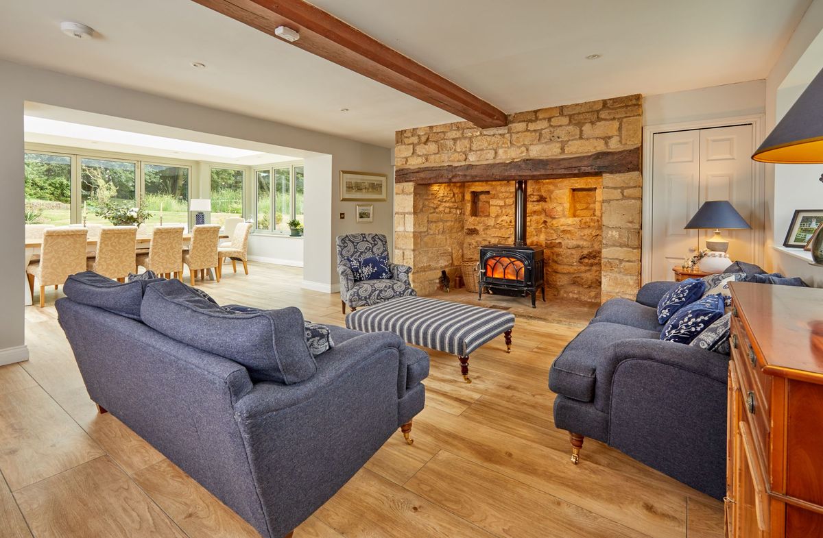 Living room with sofas facing the fireplace and wooden floors with underfloor heating