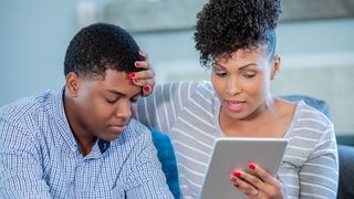 A woman sits with a man during a telehealth appointment