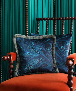 Susi Bellamy blue marbled cushion with fringed trim on orange bobbin chair