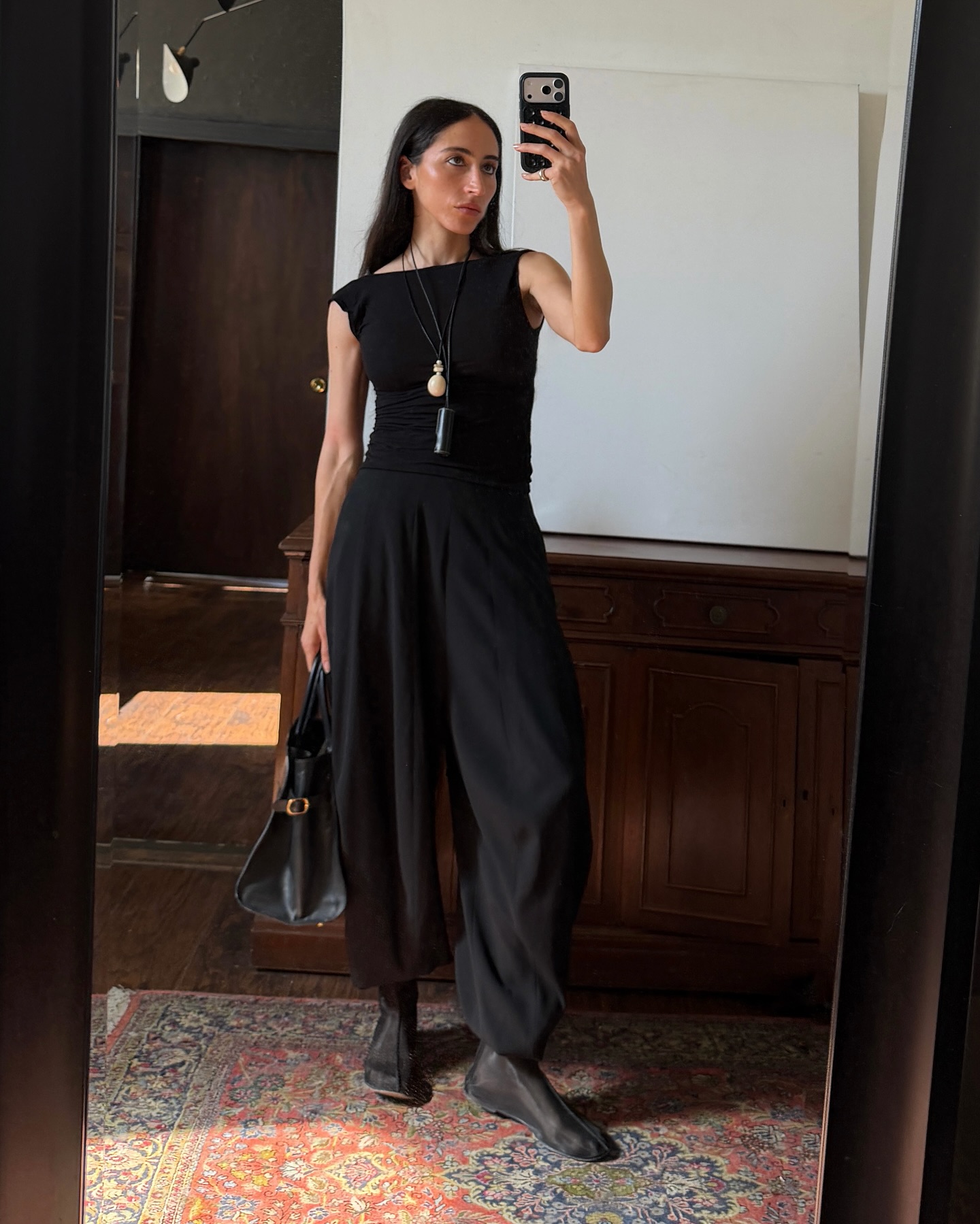 An image of @alexisbadiyi wearing mesh booties with balloon trousers and a boat-neck top and pendant necklaces.