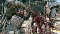An armored soldier swings a weapon at a bloodied creature in a wrecked industrial yard, amid flames and metal debris; the scene feels violent and chaotic.