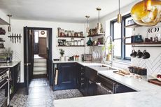 Renovated kitchen in a Victorian house, with dark cupboard doors, marble surfaces and tiled floors