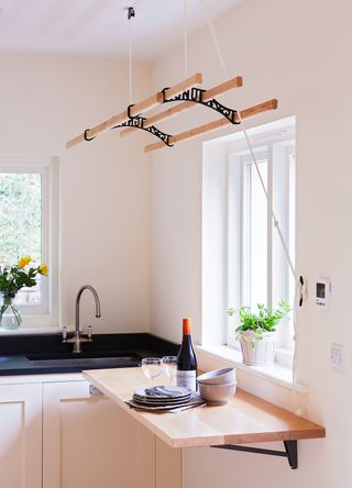 Cream kitchen with black marble countertop with folding table and ceiling mounted clothes drying rack to show space saving solutions