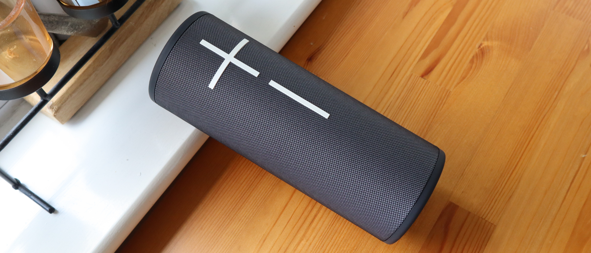 Ultimate Ears Megaboom 4 in black, in a house with white window frames in the background