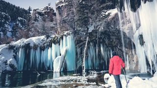 Man standing in front of frozen waterfall, Hanging lake, Colorado