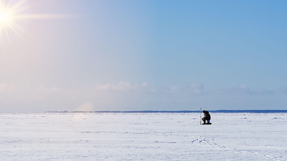 A person ice fishing at sea in Estonia