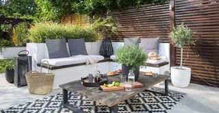 Outdoor living room with corner sofa dressed with monochrome cushions. coffee table and black and white striped rug