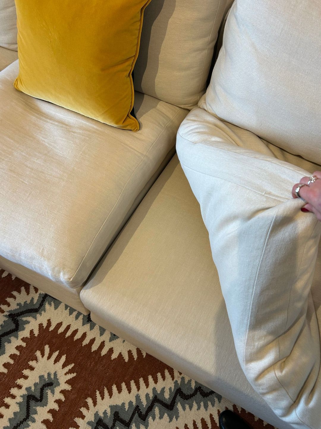 Close-up of Schplendid's Wee Bonnie sofa in light linen, showing its thick seat cushions, upholstered frame and generously filled back cushions.
