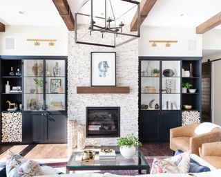 Living room with large cage ceiling pendant, and double glazed cabinets with exposed shelving either side of fireplace